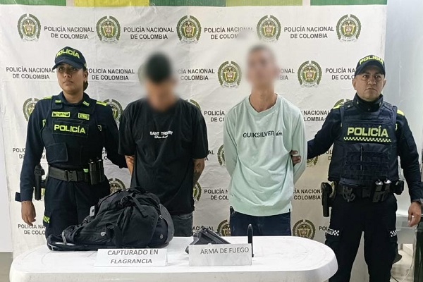 Dos polic&iacute;as custodian a dos hombres capturados