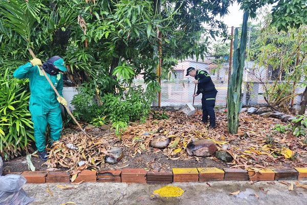 Un policía y un ciudadano barren hojas durante la recuperación y embellecimiento de un parque