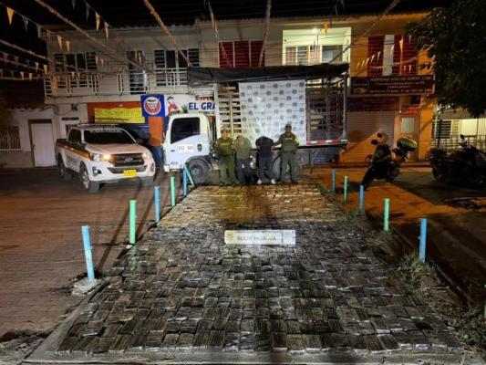 policías al lado de dos hombres con estupefacientes