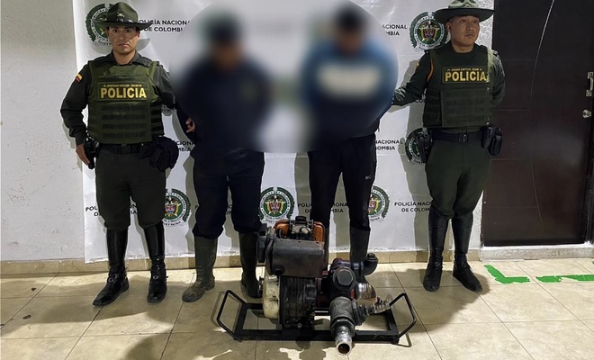 Dos ciudadanos capturados por extracci&oacute;n ilegal de recursos h&iacute;dricos , esposados con dos polic&iacute;as de Carabineros en cada lado respectivamente 