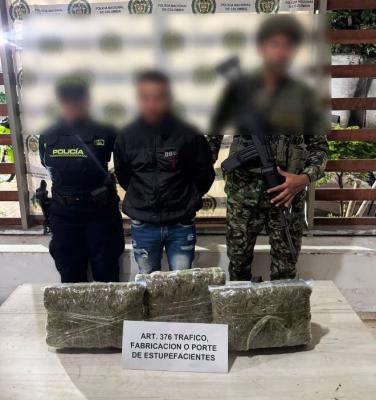 un policía un soldado al lado de un hombre capturado con estupefacientes