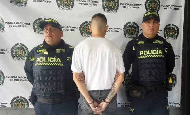 hombre_de_camiseta_blanca_capturado_en_medio_de_dos_polic&iacute;as